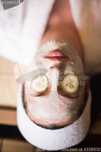 Image of woman is getting facial clay mask at spa