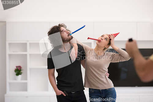 Image of couple in party hats blowing in whistle