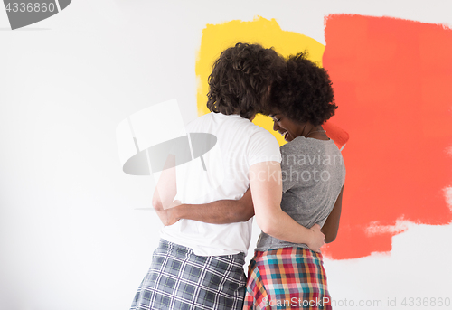 Image of multiethnic couple painting interior wall