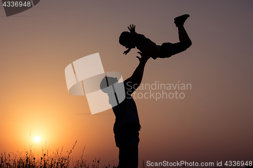 Image of Father and son playing in the park at the sunset time.