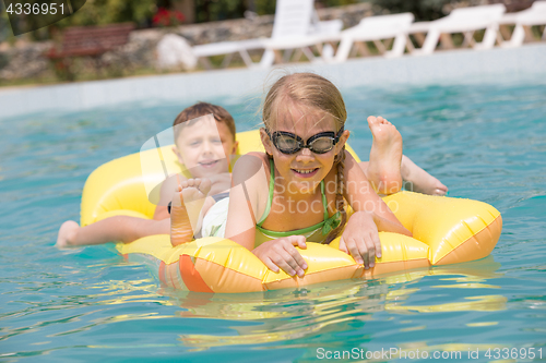 Image of Two happy children playing on the swimming pool at the day time.