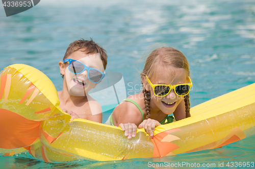 Image of Two happy children playing on the swimming pool at the day time.