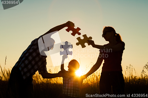 Image of Happy family playing at the park at the sunset time.