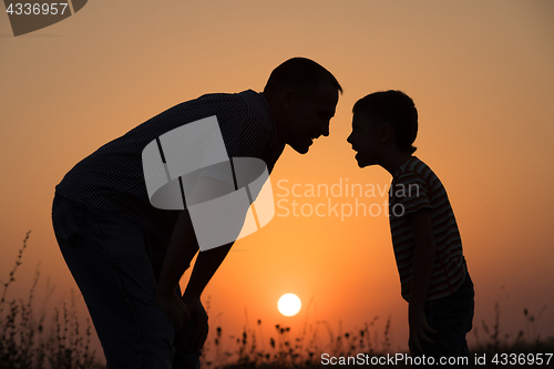Image of Father and son playing in the park at the sunset time. 