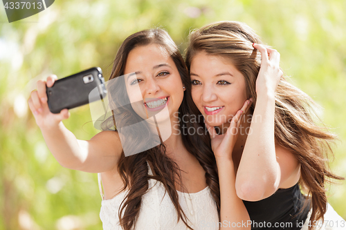 Image of Two Attractive Mixed Race Girlfriends Using Their Smart Cell Pho