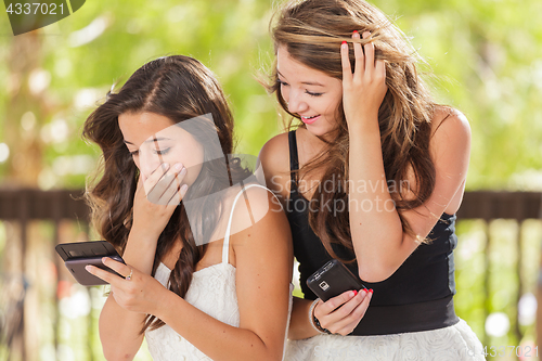 Image of Two Expressive Mixed Race Girlfriends Using Their Smart Cell Pho