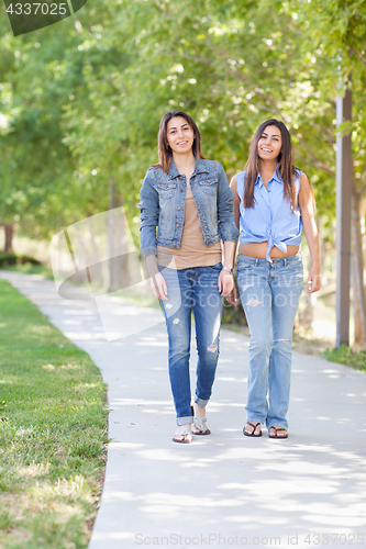 Image of Two Beautiful Ethnic Twin Sisters Walking Outdoors.