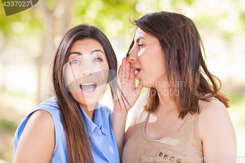 Image of Two Beautiful Ethnic Twin Sisters Whispering Secrets Outdoors.