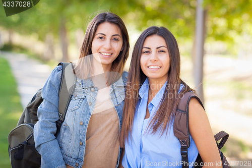 Image of Two Beautiful Young Ethnic Twin Sisters With Backpacks Walking O