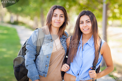 Image of Two Beautiful Young Ethnic Twin Sisters With Backpacks Walking O