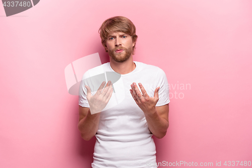 Image of Serious businessman having no idea raised his hands