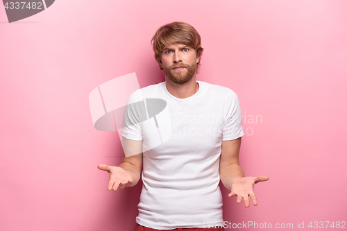 Image of Serious businessman having no idea raised his hands