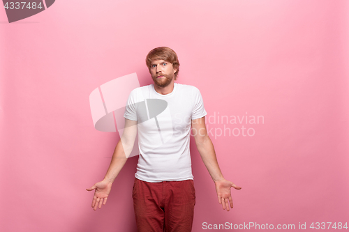 Image of Serious businessman having no idea raised his hands