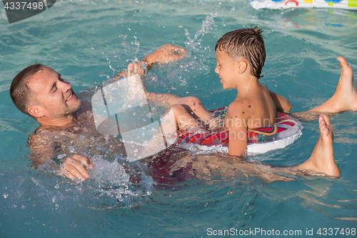 Image of Father and son  playing in the swimming pool at the day time.