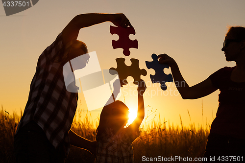 Image of Happy family playing at the park at the sunset time.