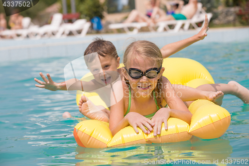 Image of Two happy children playing on the swimming pool at the day time.