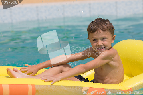 Image of happy child playing on the swimming pool at the day time.