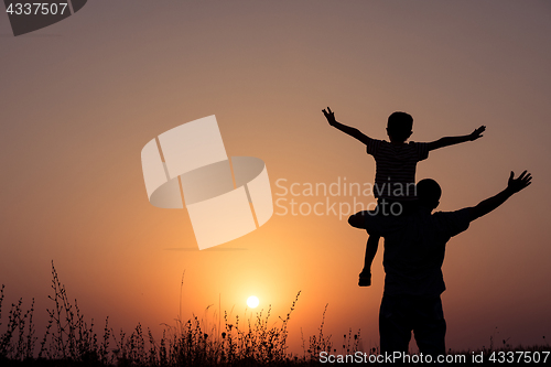 Image of Father and son playing in the park at the sunset time.