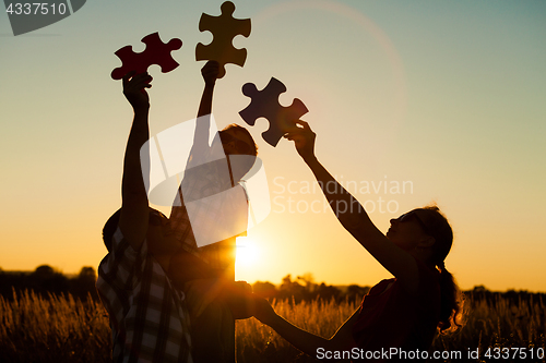 Image of Happy family playing at the park at the sunset time.