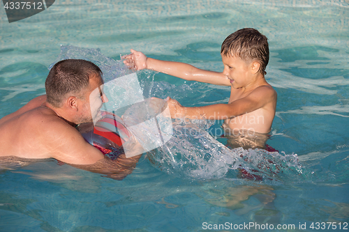 Image of Father and son  playing in the swimming pool at the day time.