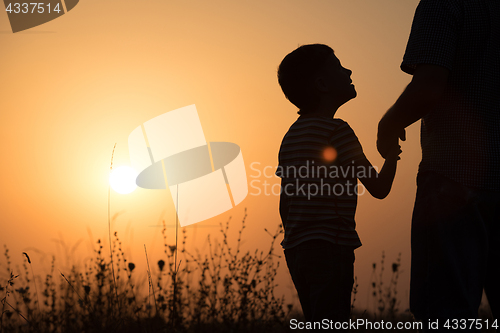 Image of Father and son playing in the park at the sunset time.