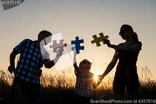 Image of Happy family playing at the park at the sunset time.