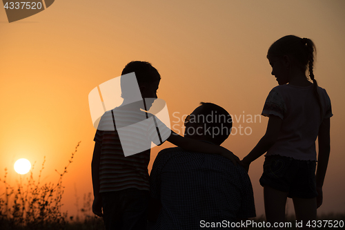 Image of Father and children playing in the park at the sunset time.