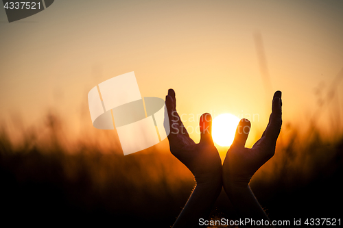 Image of silhouette of female hands during sunset. 