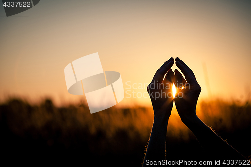 Image of silhouette of female hands during sunset.