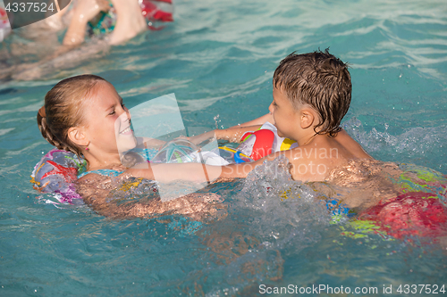 Image of Two happy children playing on the swimming pool at the day time.