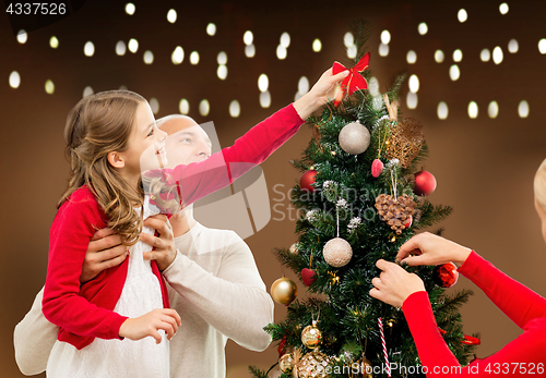 Image of happy family decorating christmas tree at home