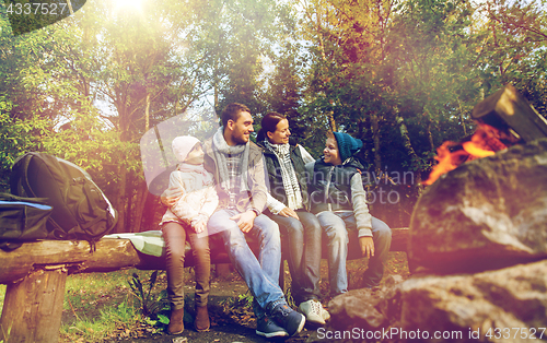 Image of happy family sitting on bench at camp fire