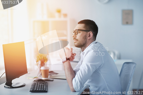 Image of businessman in glasses sitting at office computer