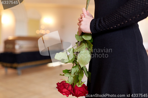 Image of close up of woman with roses and coffin at funeral