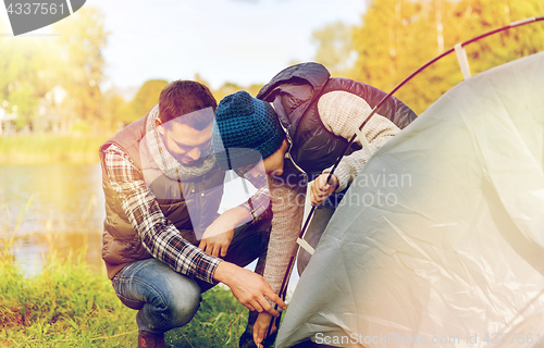Image of happy father and son setting up tent outdoors