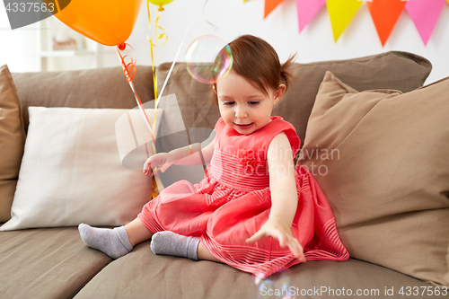 Image of baby girl with soap bubbles on birthday party