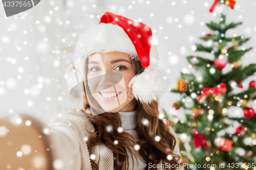 Image of woman in santa hat taking selfie at christmas