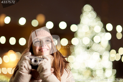 Image of happy young woman with camera over christmas tree