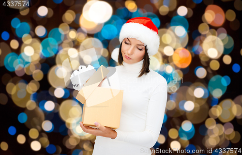 Image of displeased woman in santa hat with christmas gift