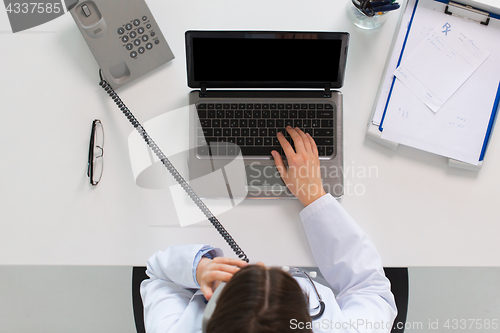 Image of doctor with laptop calling on phone at clinic