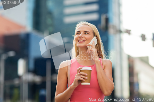 Image of woman with coffee calling on smartphone in city