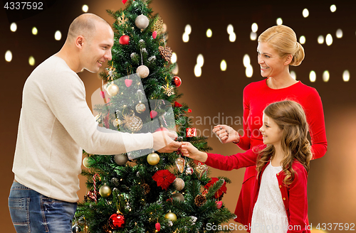 Image of happy family decorating christmas tree at home