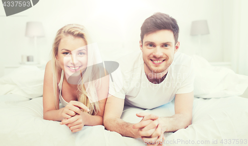 Image of happy couple lying in bed at home