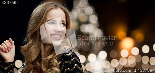 Image of happy woman dancing over christmas tree lights