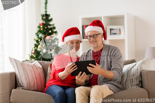 Image of happy senior couple with tablet pc at christmas