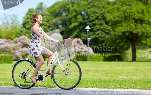 Image of happy woman riding fixie bicycle in summer park