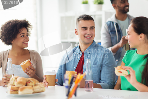 Image of happy friends or team eating at office party