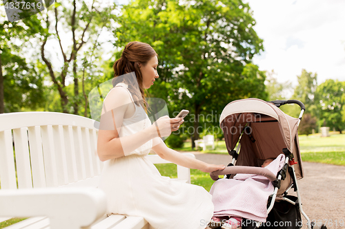 Image of happy mother with smartphone and stroller at park