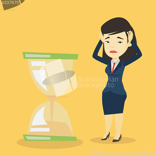 Image of Desperate business woman looking at hourglass.