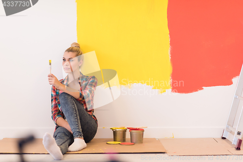 Image of young female painter sitting on floor